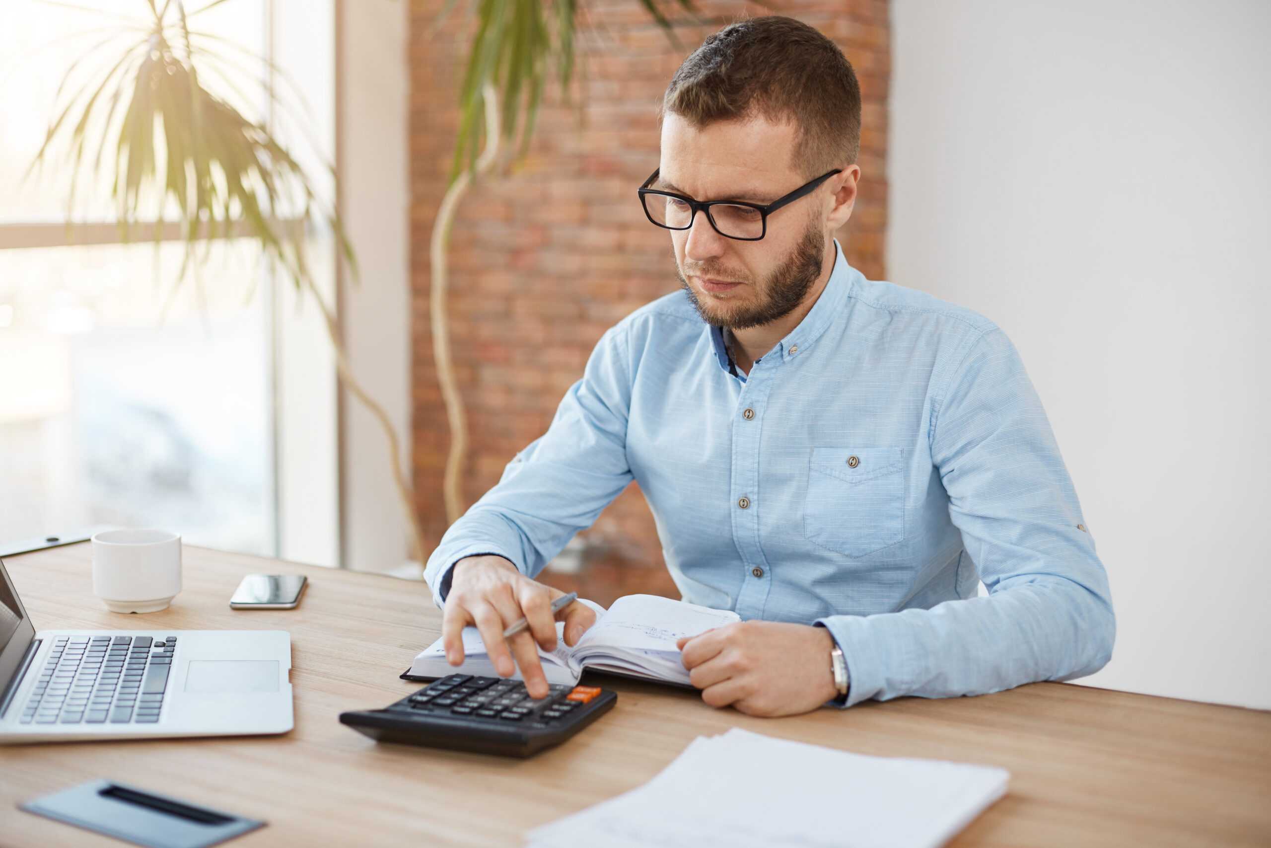 adult serious bearded caucasian finance manager glasses blue shirt sitting light comfortable company office scaled